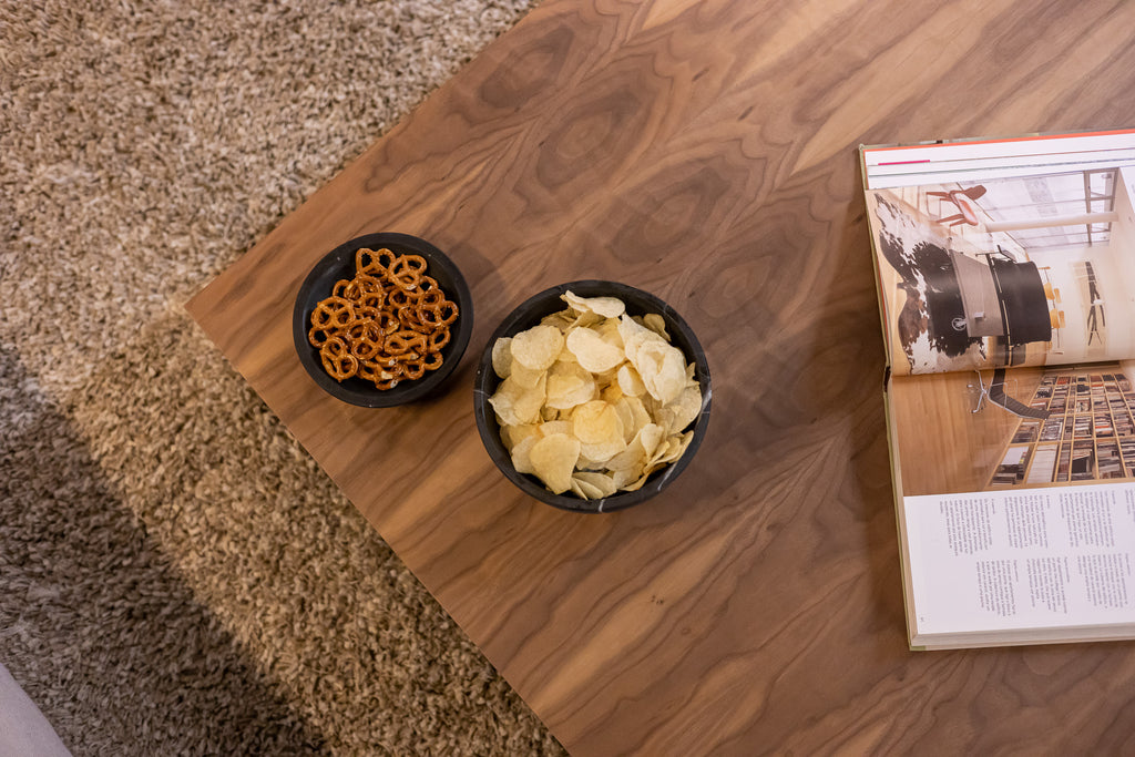 Frutero y tazón de mármol sobre mesa de comedor contemporánea.