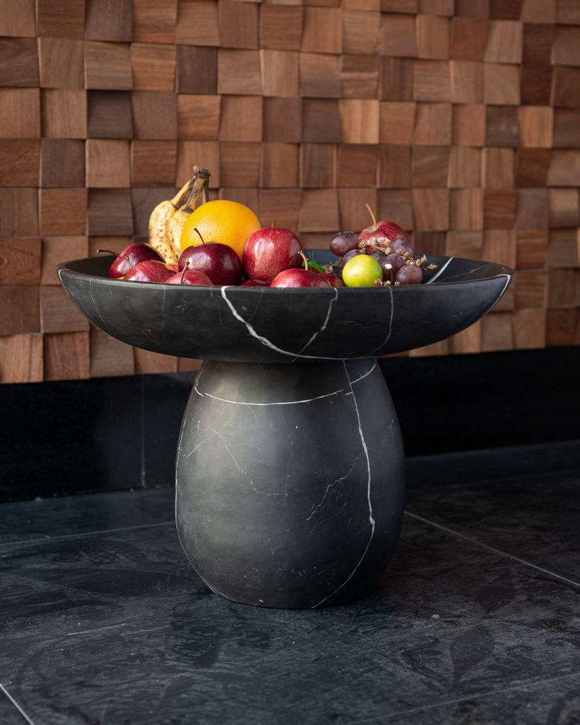Bowl de mármol con frutas frescas en una mesa moderna.
