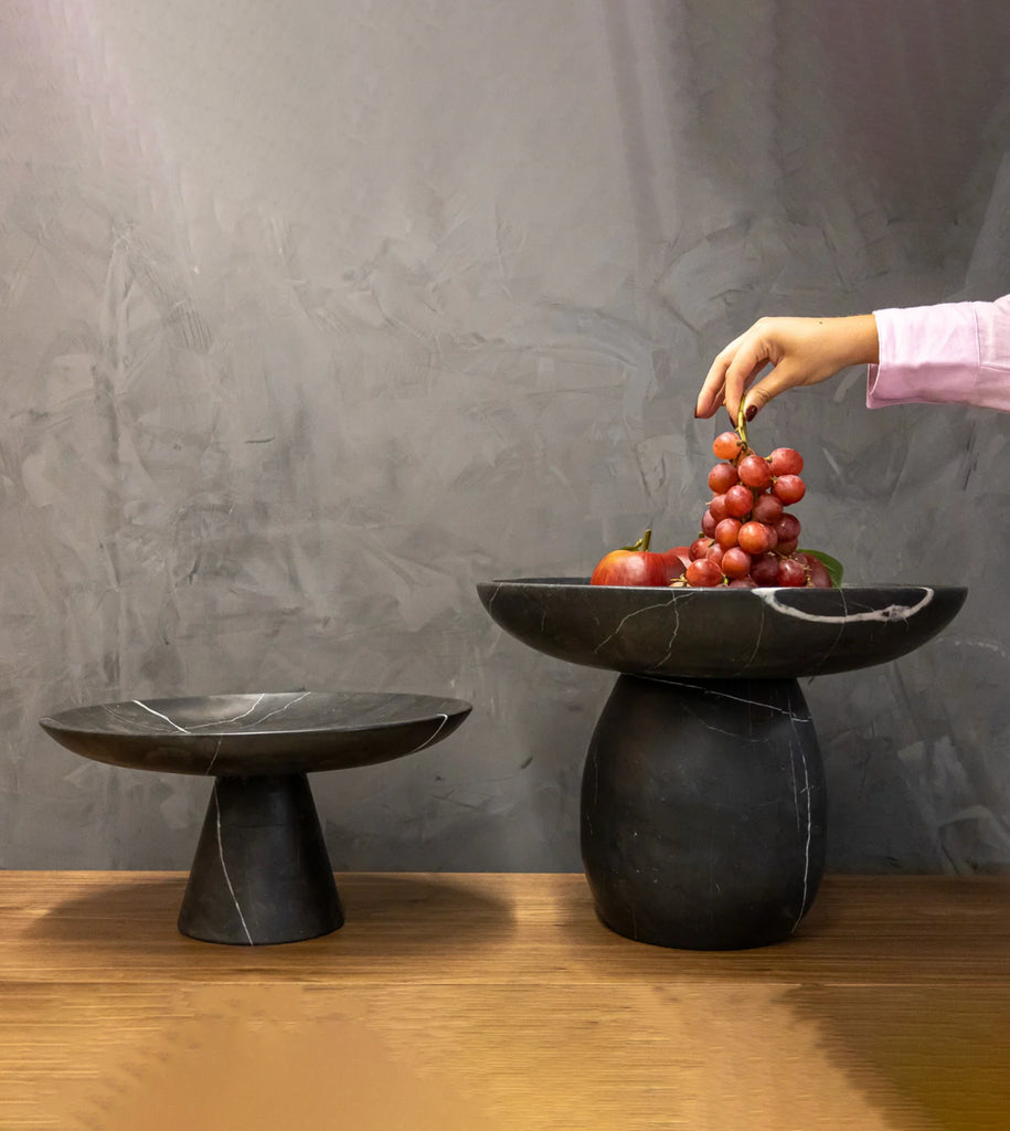 Frutero decorativo de mármol sobre un mueble clásico.