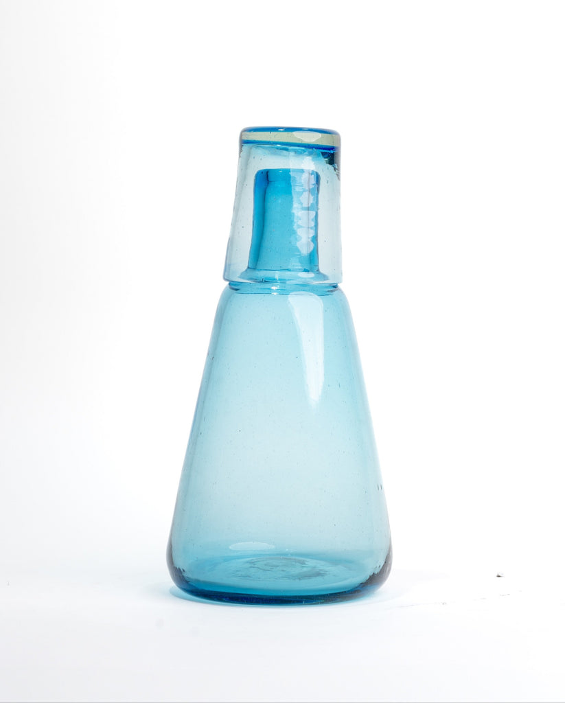 Elegante jarra para agua con diseño individual y vaso incluido, fabricada en vidrio soplado, perfecta para espacios sofisticados.